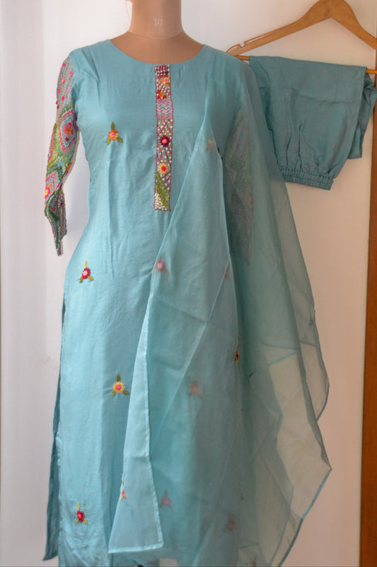 Light blue embroidered traditional outfit on a mannequin against a white wall.